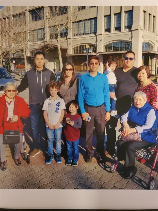 Family members smiling and posing for a photo on a sunny afternoon outdoors.