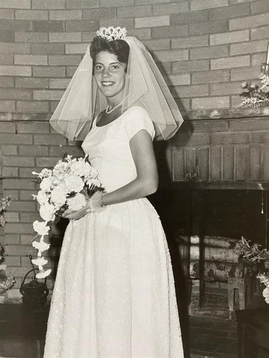 Bride stands gracefully in a vintage wedding dress, holding a bouquet, radiating joy and elegance.