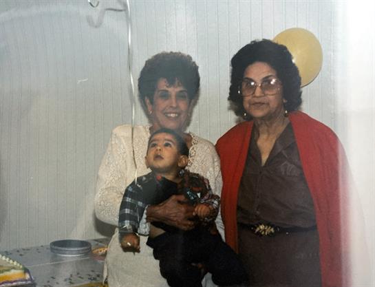 A joyful family moment with a grandmother holding her grandchild and mother celebrating together.