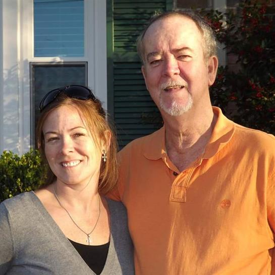 Two people pose for a cheerful photo outdoors, enjoying a sunny day in a neighborhood setting.