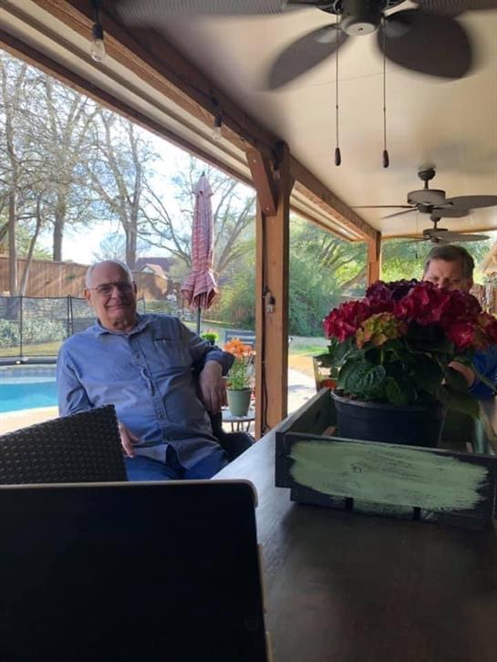 Two friends relax and chat at a table while enjoying the warm sun and refreshing pool view.