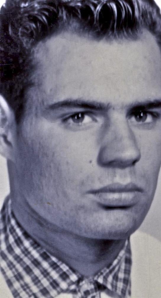 A young man with a serious expression stares directly at the camera, showcasing his features.