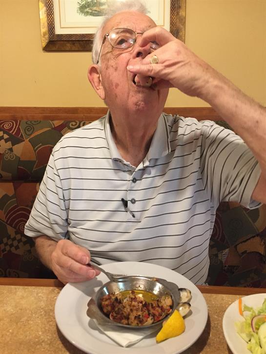 An elderly man is savoring his food while dining alone at a restaurant during lunchtime.
