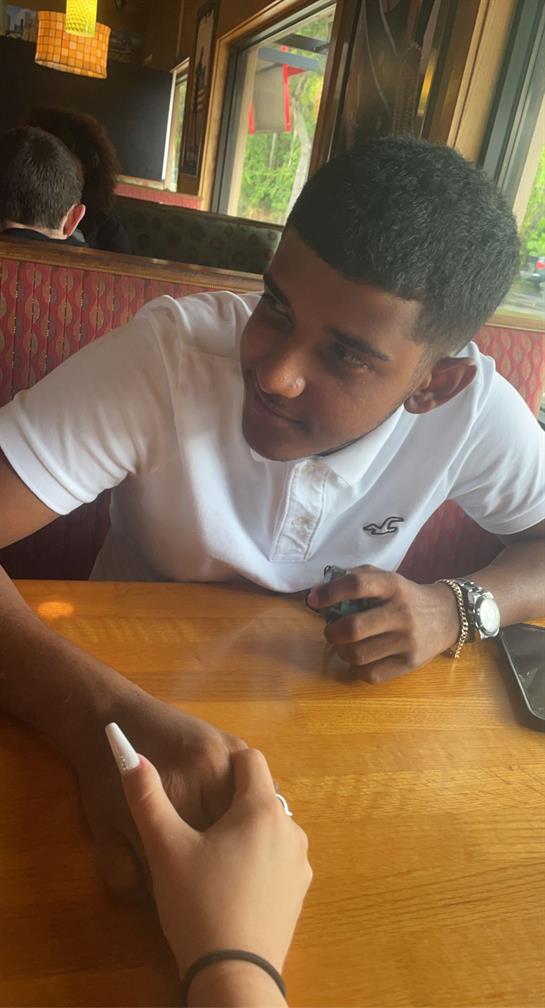 A teenager writes thoughtfully on a wooden table in a cafe, enjoying a relaxed afternoon atmosphere.