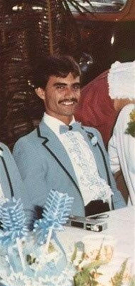A man in a light blue suit joyfully celebrates with friends at a fiesta.