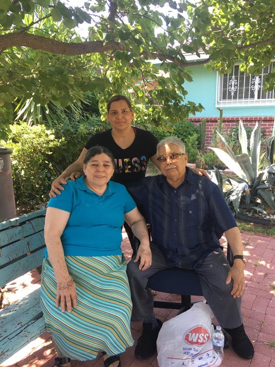 Three family members enjoy quality time together in a serene garden setting under natural shade.