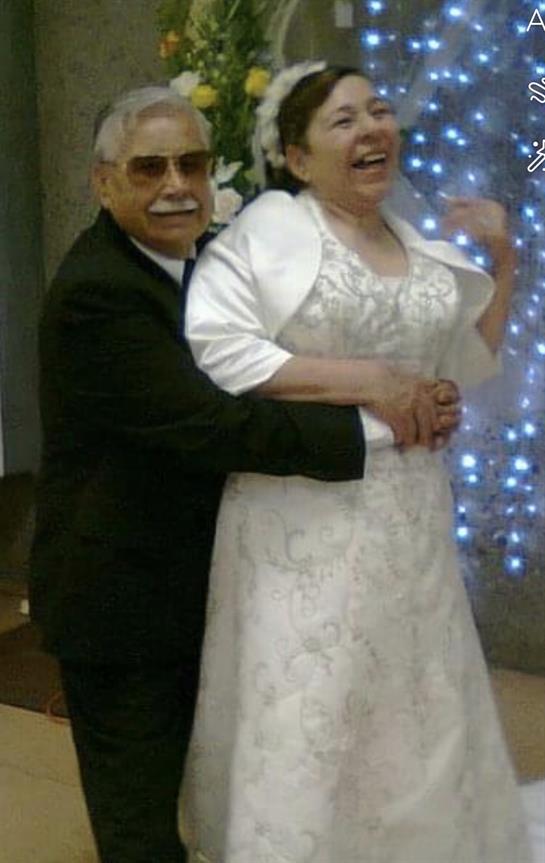 An older couple shares a heartfelt dance at a wedding, enjoying the moment under glowing lights.