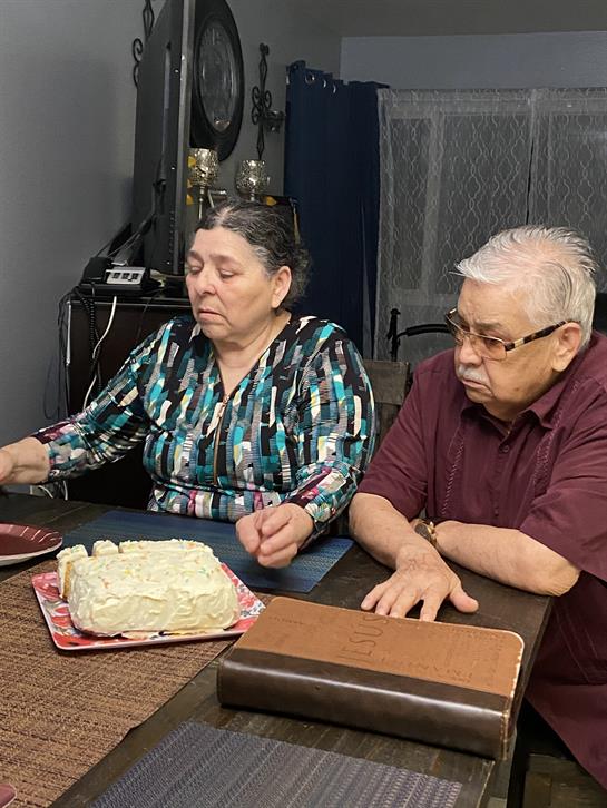 Two family members sit quietly at a table, sharing a contemplative moment over a dessert.