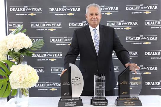 A proud dealer showcases multiple awards at an automotive recognition event.