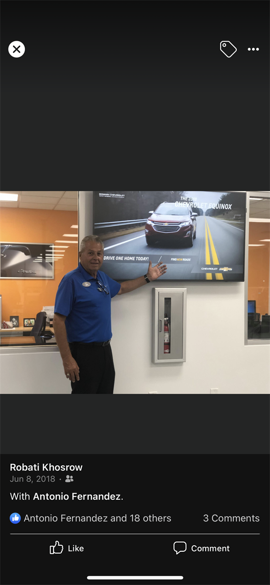 Salesperson gestures toward a digital display featuring the Chevrolet Equinox in a car showroom.
