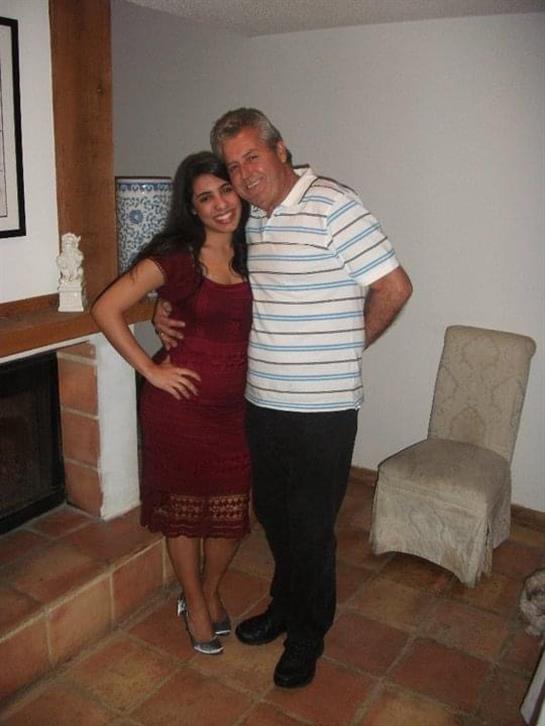 A couple stands happily together in a warm and inviting home environment, smiling at the camera.