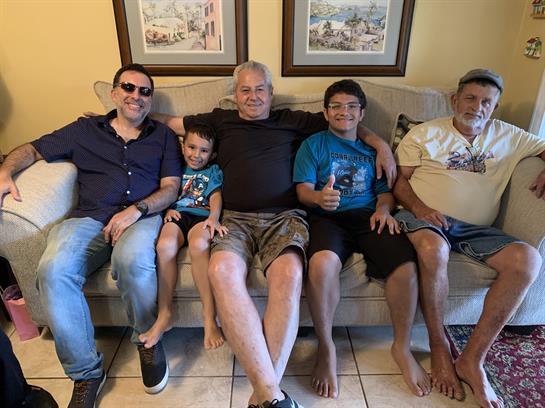 Five family members relax on a couch, sharing smiles and laughter during their visit.