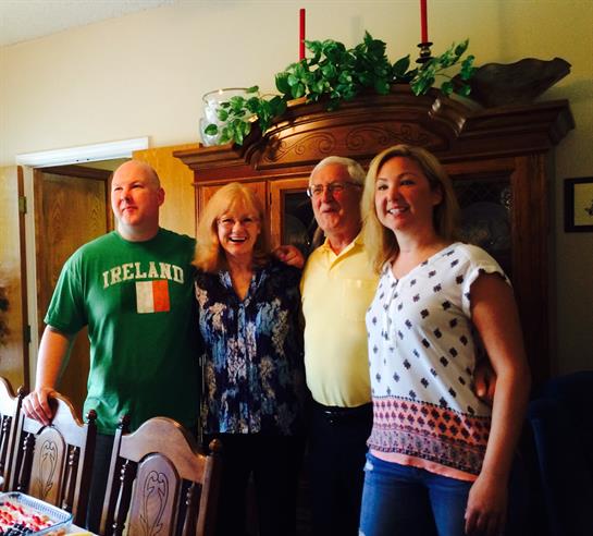 Four family members pose together in a warm dining room during a joyful gathering.