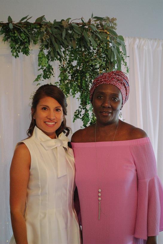 Two women stand proudly together in a decorated space, enjoying a festive gathering.