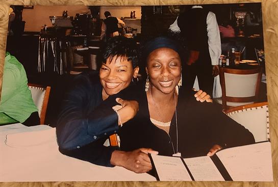 Two women share smiles and laughter at a restaurant table with menus, capturing a memorable evening.