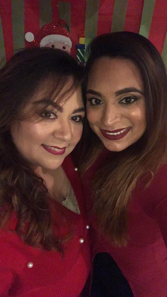 Two women pose close together, showcasing their smiles in coordinated outfits at a joyful event.
