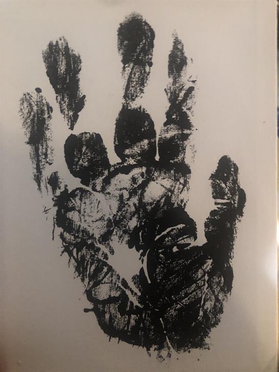 A unique black handprint on textured paper showcases creativity and art.