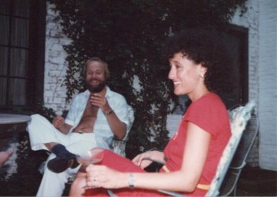 Two individuals are engaged in a friendly conversation while seated outdoors, enjoying the sunshine.