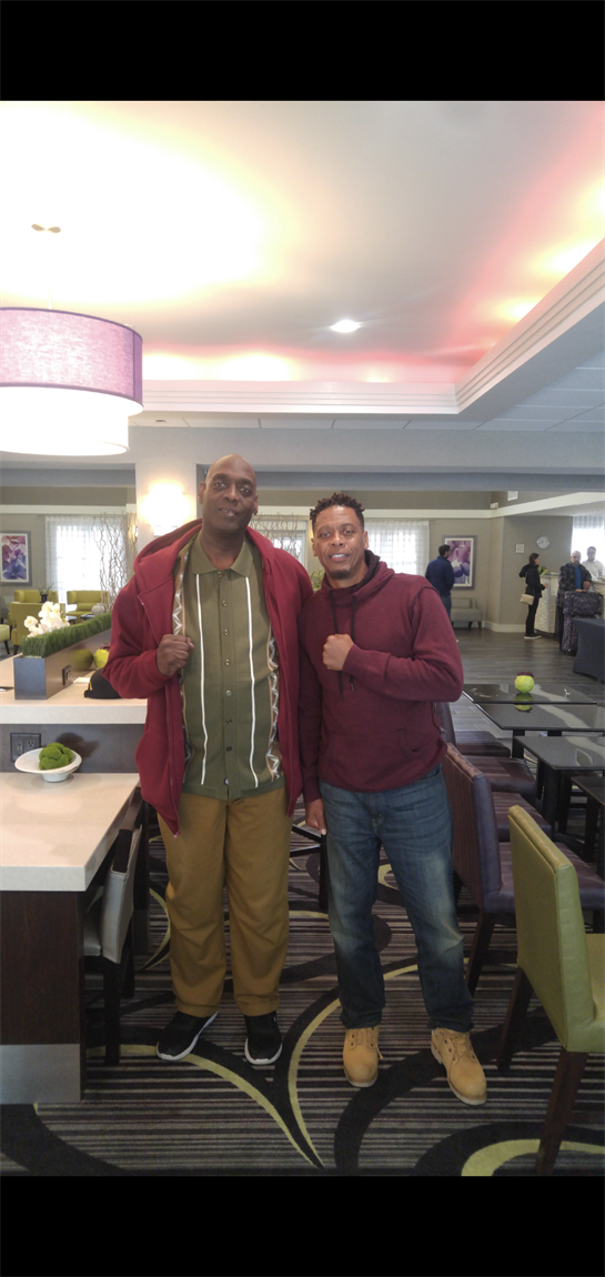 Two people smile together in a modern hotel lobby.