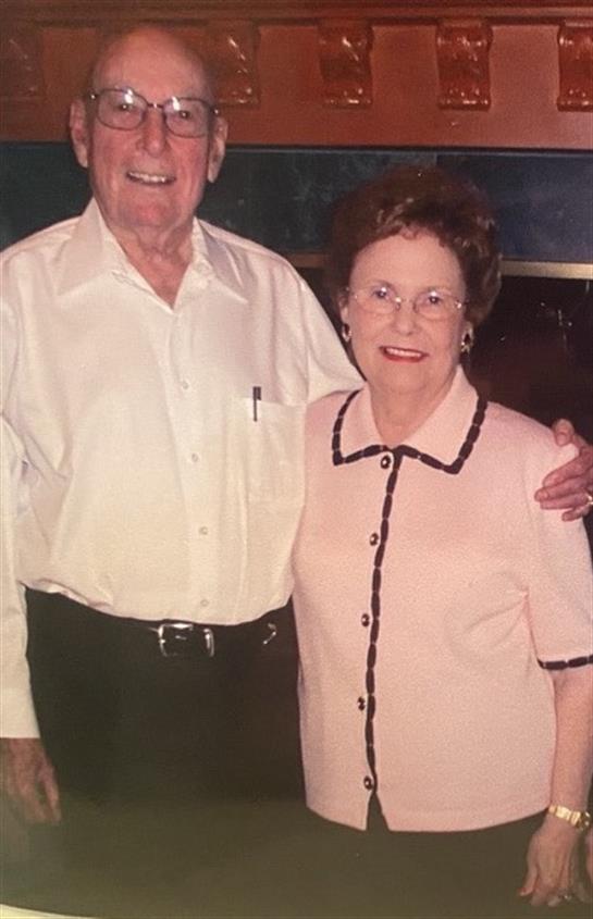 An elderly couple smiles together, showcasing affection and companionship at a gathering.