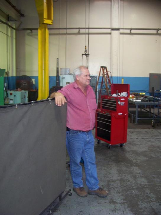 Man stands in a workshop, observing machinery and tools, showcasing an industrial work environment.