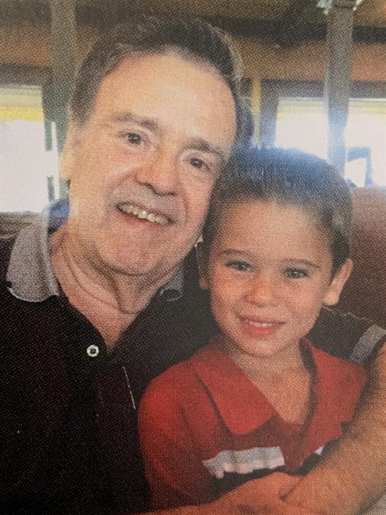 A smiling grandfather and his grandson pose closely, celebrating family bonds indoors.