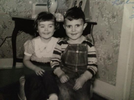 Two smiling children pose together in a cozy living room filled with retro decor.