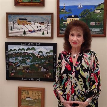 An art lover proudly stands by local paintings in a gallery, celebrating creativity.
