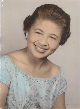 A cheerful woman wearing a beautiful blue dress smiles warmly, highlighting her charm.