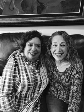 Two friends share a joyful moment while sitting on a couch at home, surrounded by comfort.