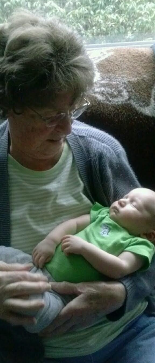 A grandmother softly gazes at her sleeping grandchild, creating a tender and loving atmosphere.