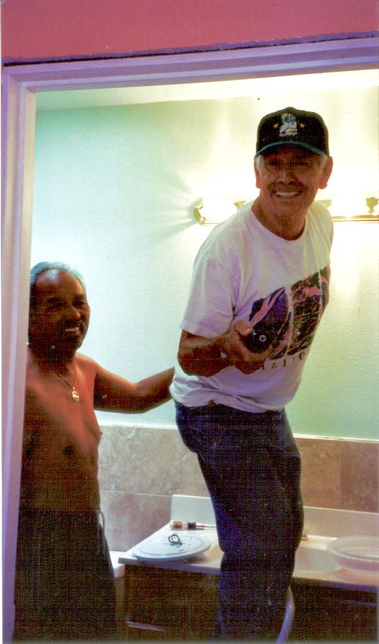 Two men are enjoying a playful moment in a bathroom at home, showcasing camaraderie and laughter.