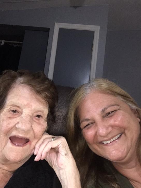 Two women share laughter and happiness while posing closely in a warm, intimate setting.