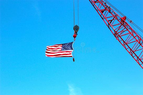 A crane lifts an American flag high, symbolizing pride during construction work.