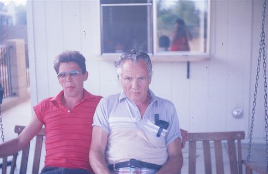 Two individuals relax on a bench, enjoying the warm weather in a simple outdoor location.