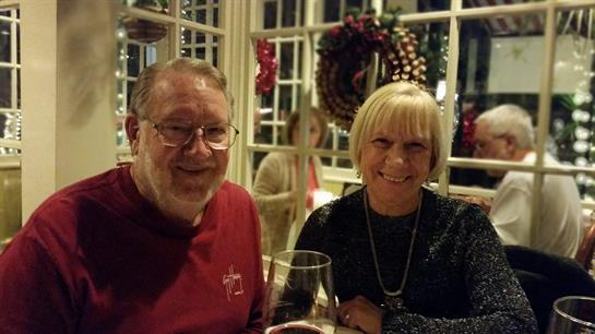 A joyful couple enjoys drinks together at a festive gathering, surrounded by holiday decorations.
