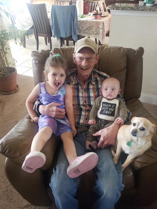 Warm moment shared between grandfather, two grandchildren, and a dog in a comfortable chair.