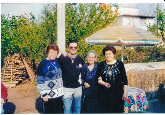 A group of four people enjoy a sunny day in a garden, sharing laughter and fond memories.