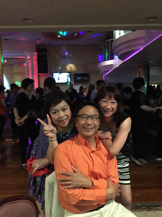 Friends pose together happily in a busy venue glowing with colorful lights during a night out.