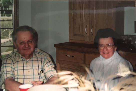 An elderly couple shares a meal at a warm, inviting table, celebrating time together with family.