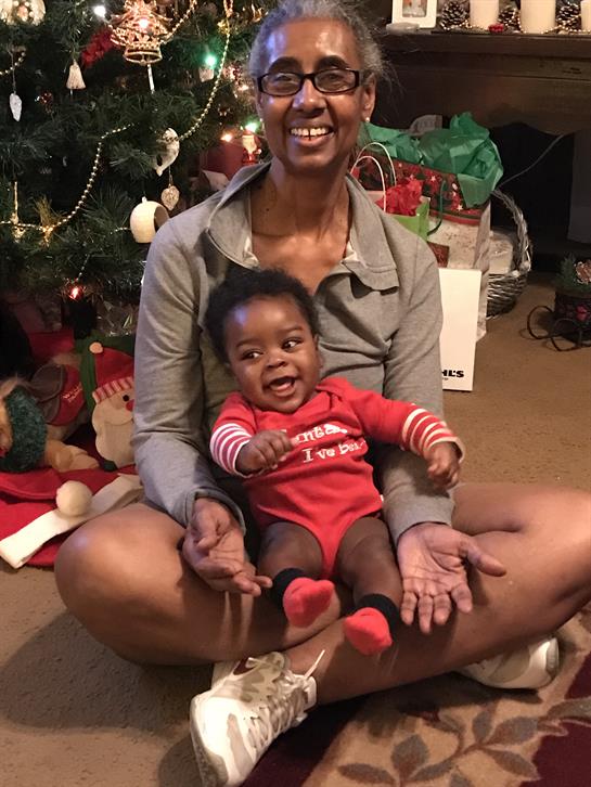 Joyful moments are shared as a caregiver holds a laughing child by the Christmas tree.