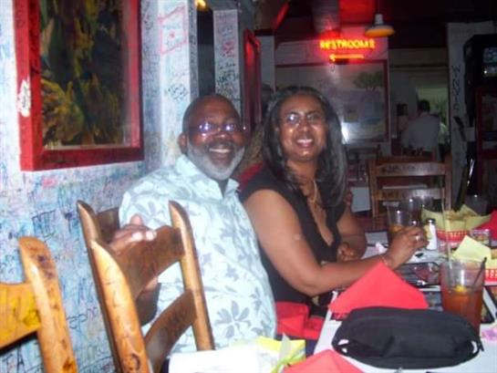 Two smiling individuals share a joyful moment at a restaurant, enjoying their meal together.