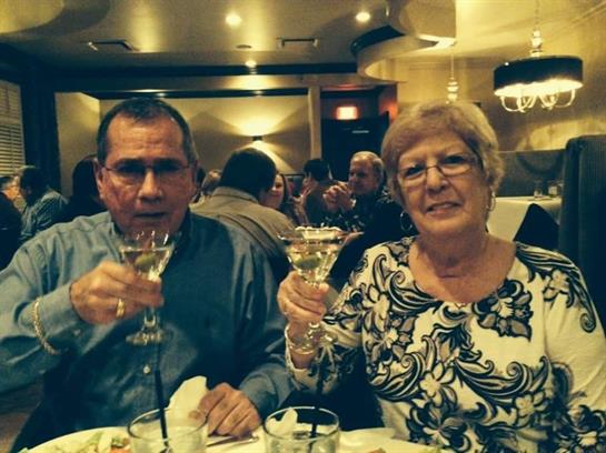 Two people raise their glasses in celebration at a lively restaurant during dinner time.
