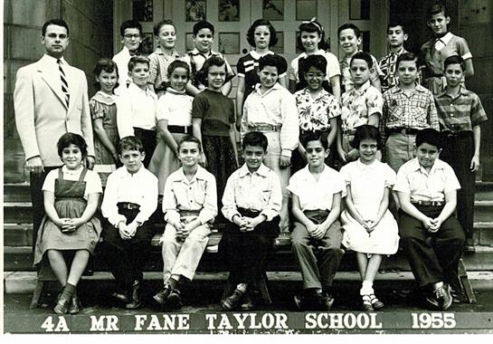 Children and their teacher smile for a group photo in front of Fane Taylor School during the 1950s.