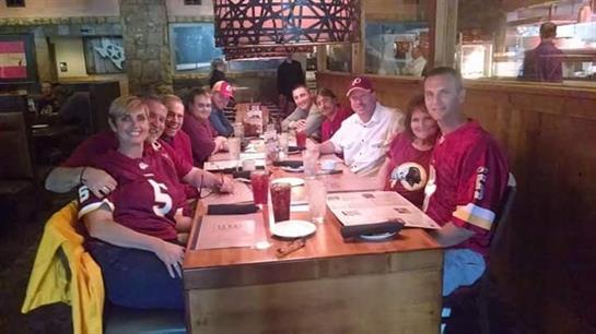 Friends in jerseys gathered around a wooden table, enjoying a festive meal together.
