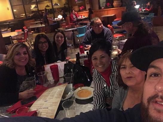 Friends share laughter and conversation while dining together at a busy restaurant setting.