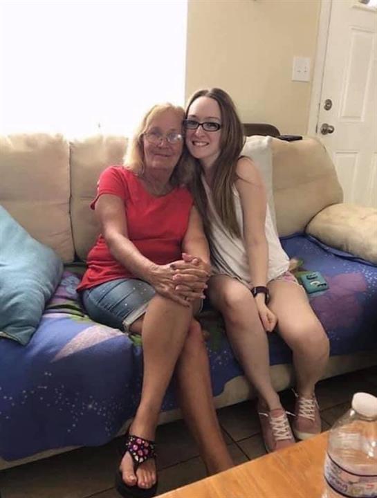 Two women are happily smiling and enjoying each other's company on a cozy couch.