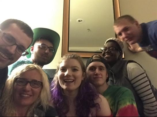 Friends gather together, smiling joyfully in a friendly indoor atmosphere at night.