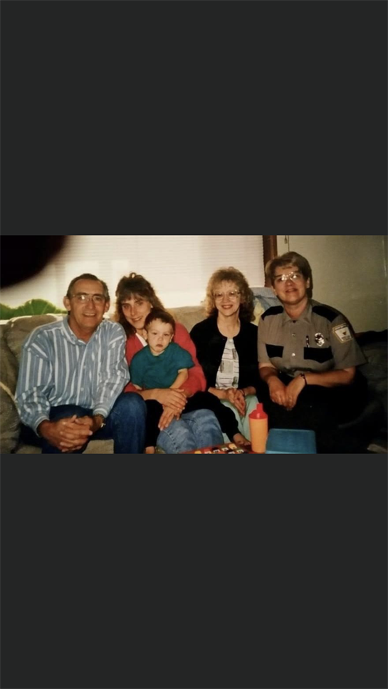 Five family members sit together in a cozy living room, sharing smiles and laughter.