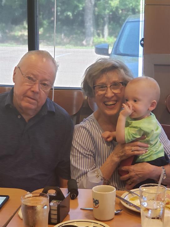 Smiling grandparents enjoy quality time with their grandchild at a local cafe during midday.